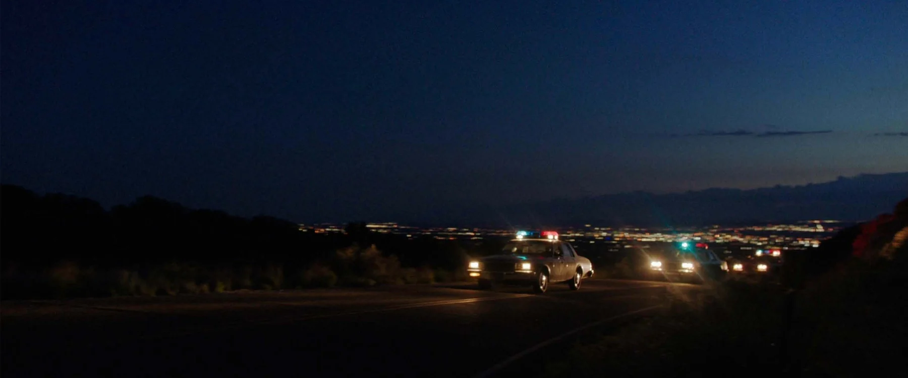 Traffic moves along a broad road beneath a fading evening sky.